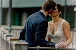 Couple kissing by railing in lace dress