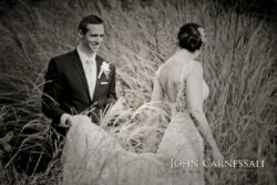 Bride in lace gown walking through grasses