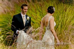 Groom smiling as he lifts bride's train