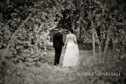 Bride and groom walking through wooded path.