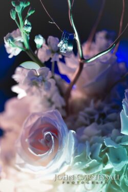 Roses and wedding rings on floral arrangement.