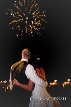 Couple watching fireworks, embracing at night.