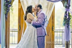Couple kissing beneath purple floral arch