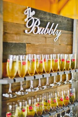 Champagne glasses on wooden display with raspberries.