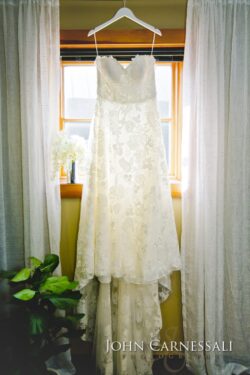 Lace wedding dress hanging by window.