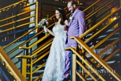 Bride and groom descending decorated staircase.
