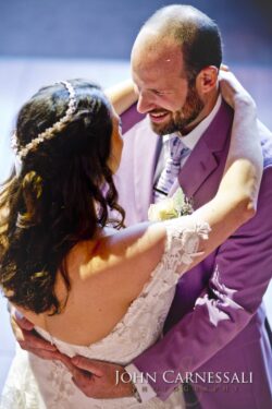 Bride and groom dancing, smiling at wedding.
