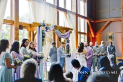 Indoor wedding ceremony with bridal party gathered.