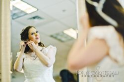 Bride adjusting earrings in front of mirror.