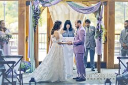 Couple holding hands beneath floral arch