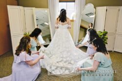 Bride with bridesmaids adjusting her wedding dress.