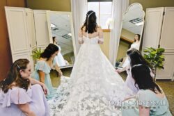 Bride with bridesmaids adjusting wedding dress.