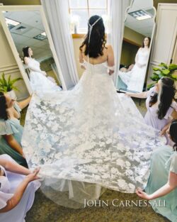 Bride with bridesmaids adjusting lace wedding dress.