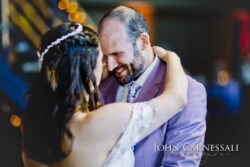 Groom in lavender suit smiling during first dance