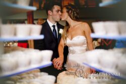 Bride and groom kissing near wedding cake.