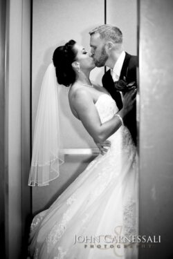 Groom embraces veiled bride for elevator kiss