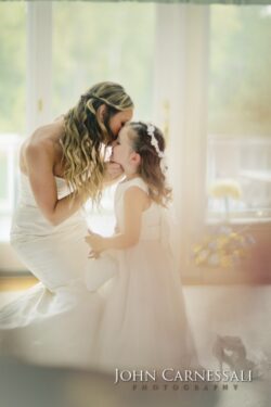 Bride kissing young girl in white dress.