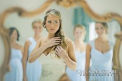 Bride preparing with bridesmaids in background reflection.