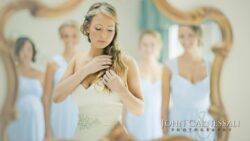 Bride adjusting hair with bridesmaids reflected