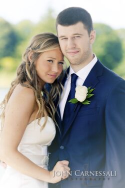 Bride and groom embracing outdoors, smiling.