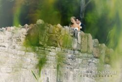 Bride and groom standing on stone bridge.