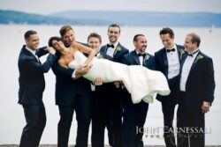 Groomsmen holding bride by a lake.