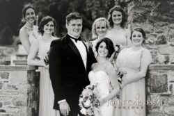 Wedding party posing by stone wall.