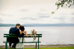 Bride and groom sitting by the lake.