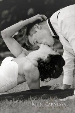 Bride and groom kissing on grass.