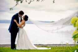 Bride and groom with flowing veil lakeside