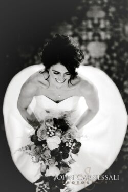 Bride smiling, holding bouquet in black and white.