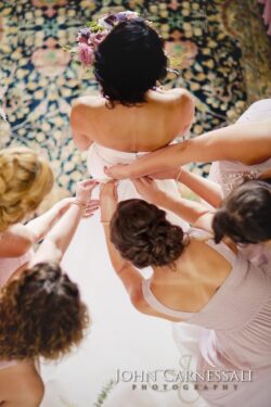 Bridesmaids helping bride with her dress.