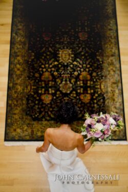 Bride holding bouquet, standing on ornate rug.