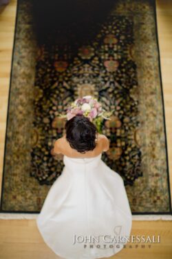 Bride holding bouquet on patterned rug.