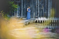 Pregnant woman standing on a boardwalk in a long blue dress