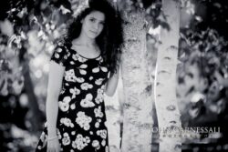 Black and white senior portrait of a girl standing near trees
