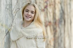 Smiling girl standing beside a tree
