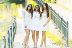 Three girls in white dresses walking together outdoors