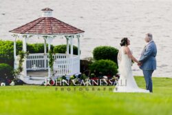 Bride and groom posing near a waterfront gazebo