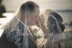 A moody silhouette image of the couple embracing with soft light and shadow.