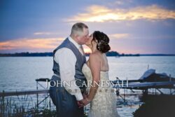 Bride and groom standing near the harbor.
