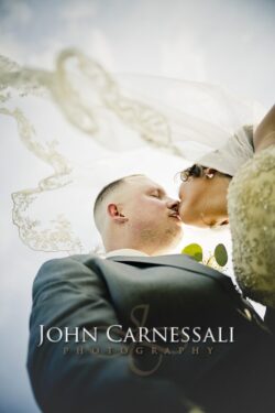 Bride and groom embracing through a sheer wedding veil.