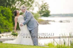 Bride and groom embracing near the waterfront.