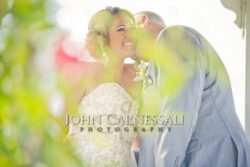 Bride and groom embracing in a soft-focus outdoor portrait.