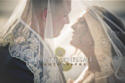 Bride and groom embracing behind the bridal veil.