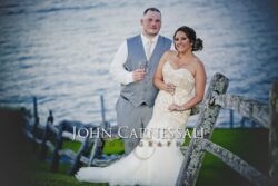 Bride and groom standing together in a waterfront portrait.