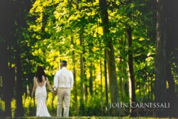 Alt Text: Bride and groom walking away beneath tall trees