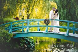 Bride and groom standing on a blue bridge surrounded by greenery