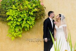 Bride and groom standing together near ivy-covered greenery