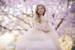 Young girl standing beneath pink blossoms